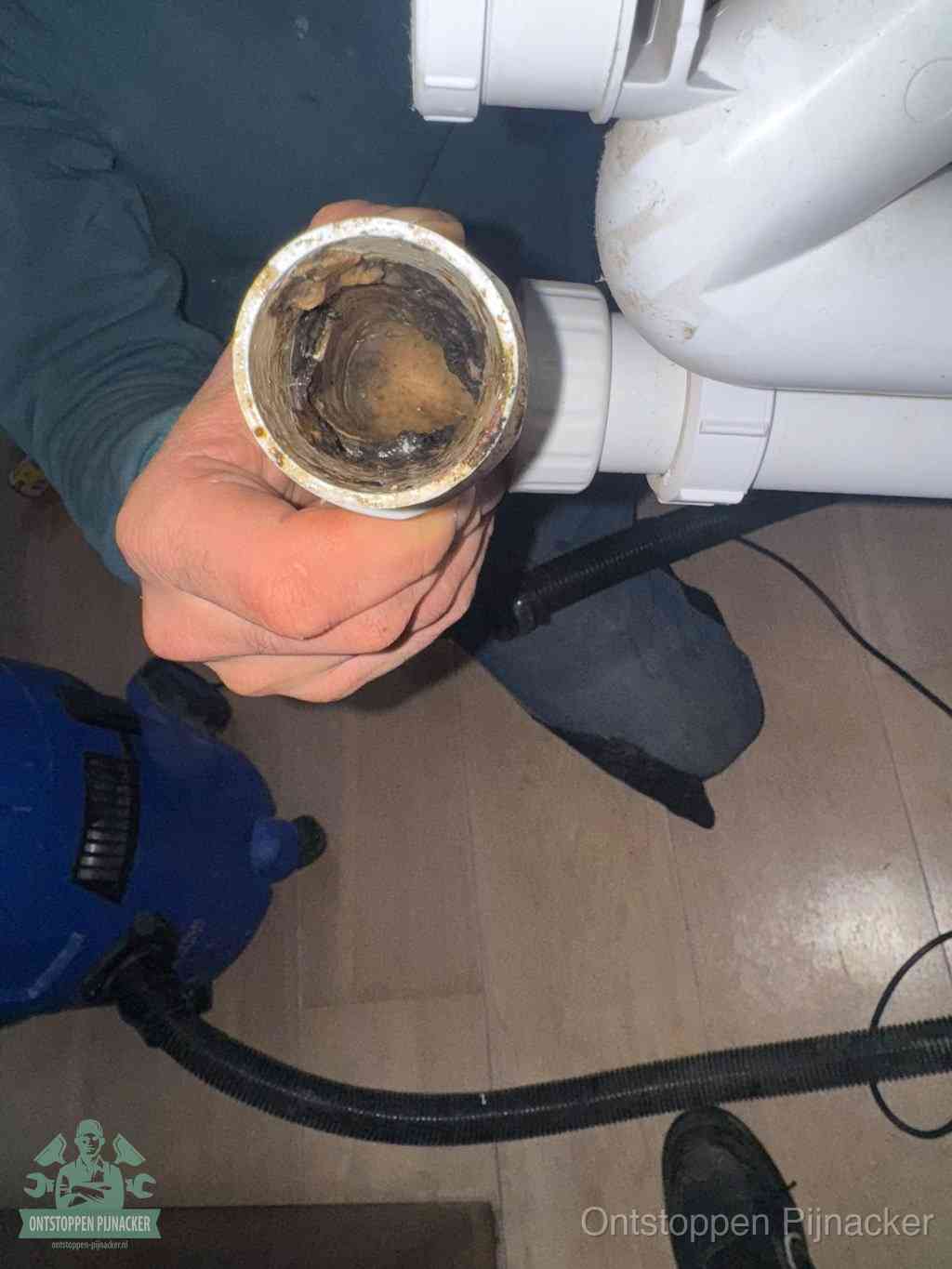 Een losgekoppeld PVC-afvoerbuisstuk dat van binnen volledig is dichtgeslibd met vet en vuil, de meest voorkomende oorzaak van verstoppingen in Pijnacker