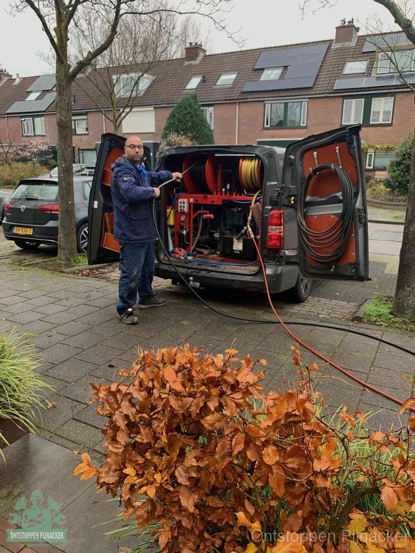 Een monteur staat bij zijn open bestelbus met hogedruk-rioolreinigingsapparatuur, klaar om binnen 30 minuten uit te rukken voor een spoedverstopping in Pijnacker