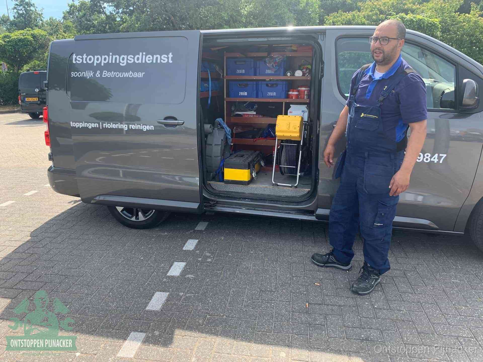 Een monteur staat klaar bij zijn bedrijfsbus met gereedschap, de vaste werkwijze van de ontstoppingsdienst in Pijnacker